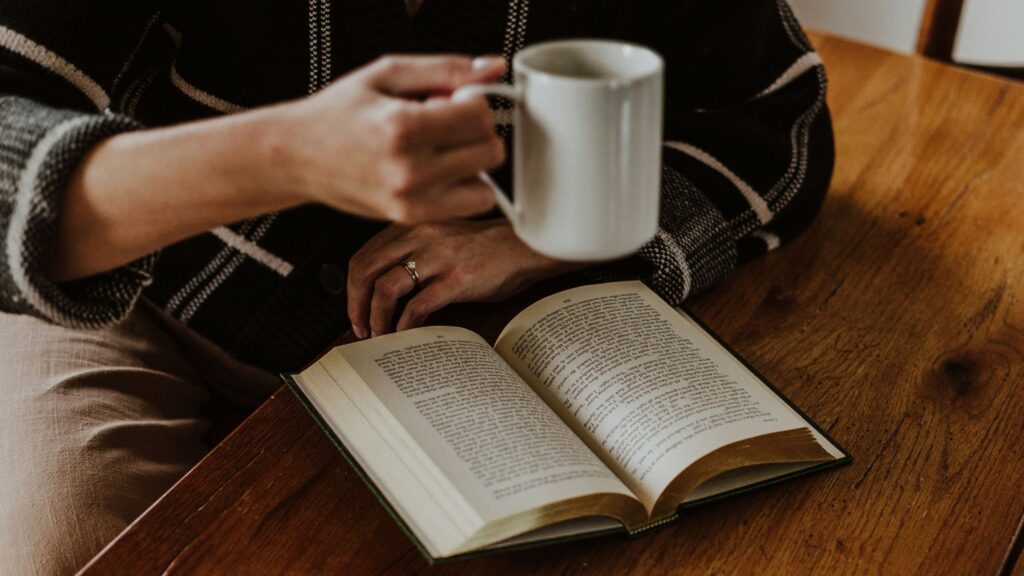 a lady reading a book and drinking a coffee